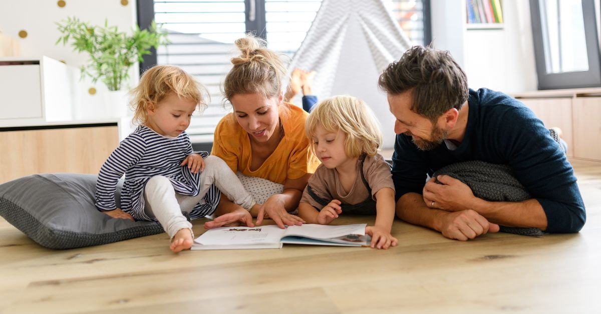 A family sits on the floor, reading a book together, sharing smiles and enjoying quality time.