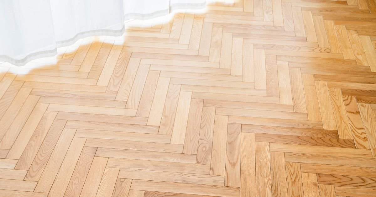 Close-up of a wooden floor with a flowing white curtain draped nearby, creating a warm and inviting atmosphere.