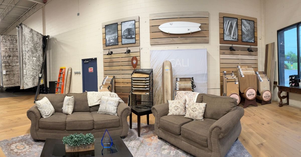 CALI Display in the Floors USA showroom featuring various furniture pieces and surfboards mounted on the wall, creating a beach-themed atmosphere.