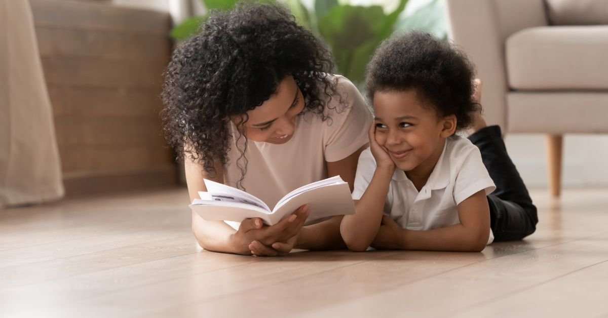 A woman and a child sit on the floor, engrossed in reading a book together.