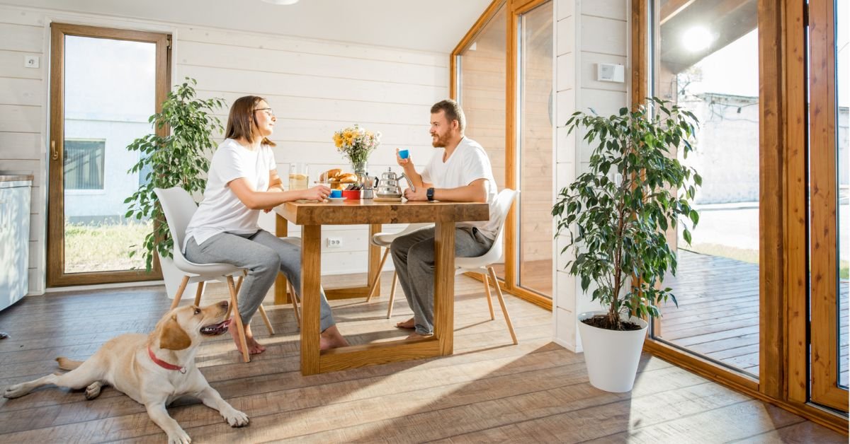 A couple sits at a table with their dog, enjoying a meal together in a cozy setting.