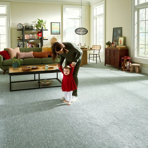 Mother helping her baby walk on plush carpet floors