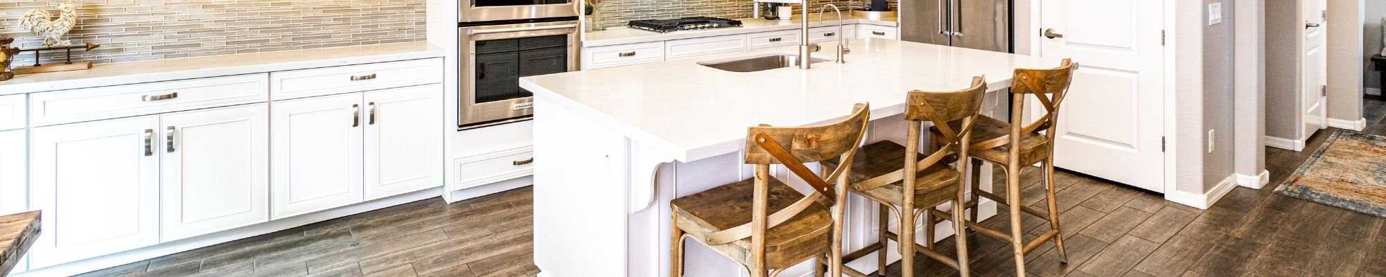 A modern kitchen featuring a white island and warm wooden flooring, creating a bright and inviting atmosphere.