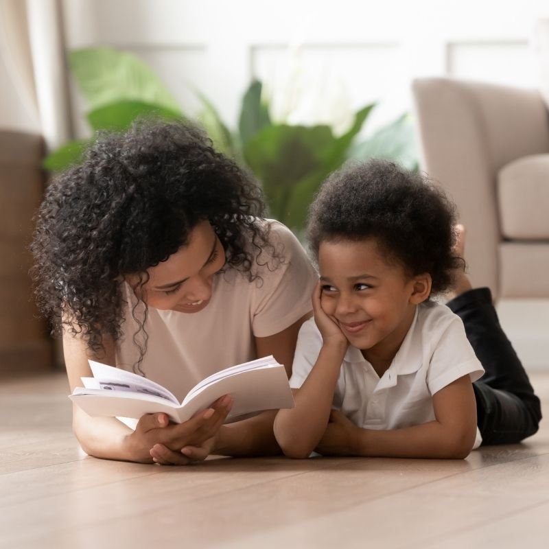 A mother and her son read a book side by side, illustrating a nurturing moment of shared knowledge and enjoyment.