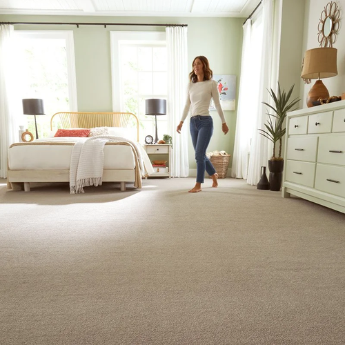 Woman smiling and walking across a carpeted bedroom