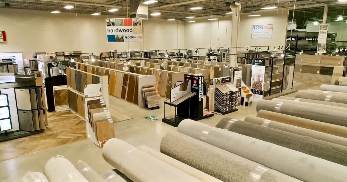 A spacious store showcasing a variety of flooring options, including tiles, hardwood, and carpets.