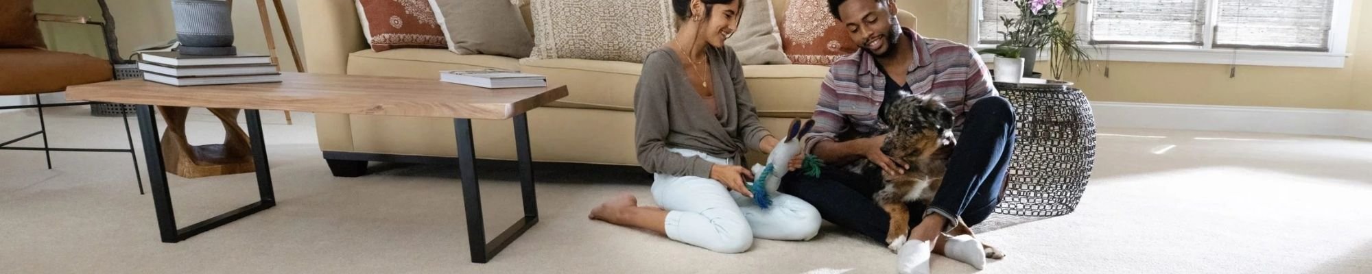 Two people sitting on the Mohawk carpet in front of a couch, engaged in conversation and enjoying each other's company.