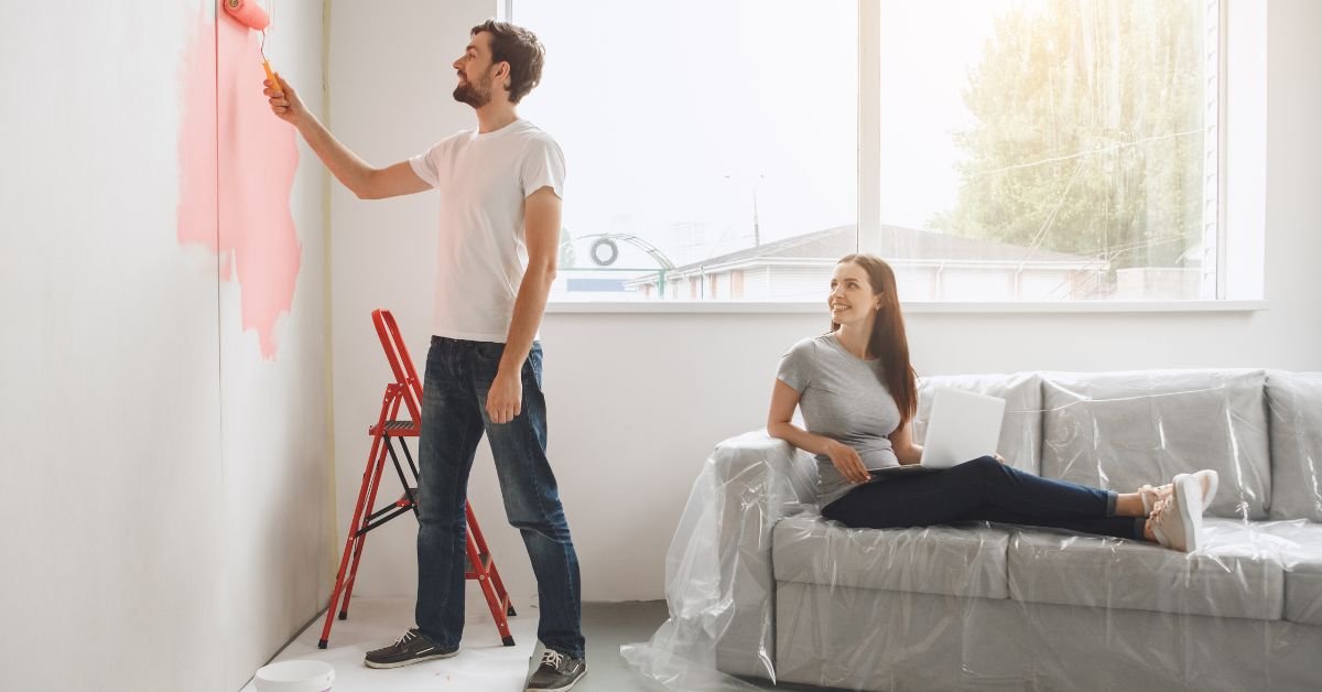 A man and woman are painting a room together, using brushes and rollers to apply color to the walls.