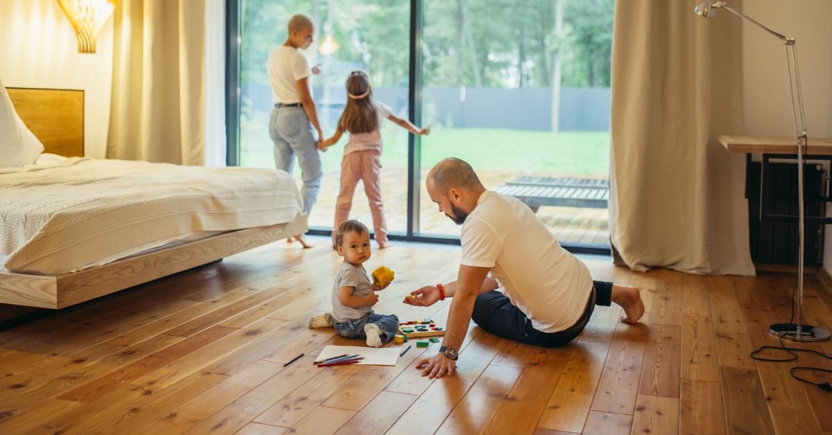 A man and woman play with their child on the floor, engaging in a joyful family moment together.