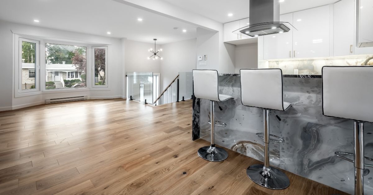 A stylish kitchen with polished marble countertops and contemporary white stools arranged around the island.
